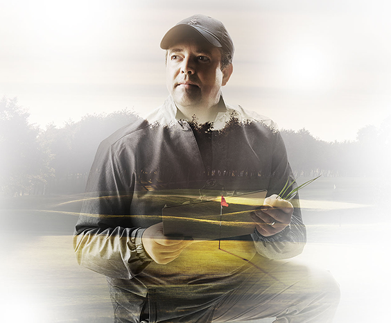A man holding a tablet while on a golf course.